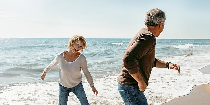 Paar mittleren Alters, das am Strand spielt und Spaß hat.