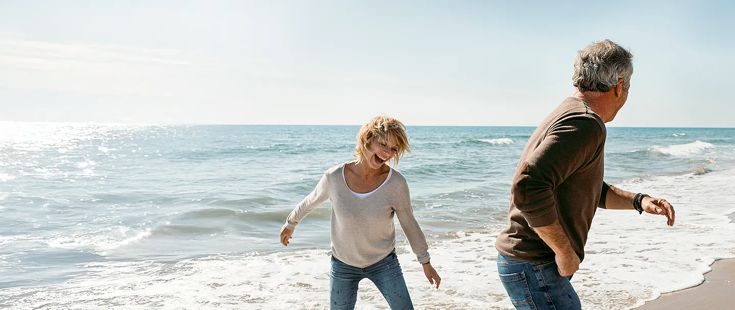 Paar mittleren Alters, das am Strand spielt und Spaß hat.