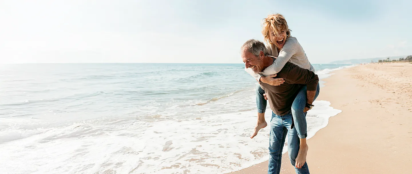 Glückliches Paar Huckepack am Strand im Herbst.